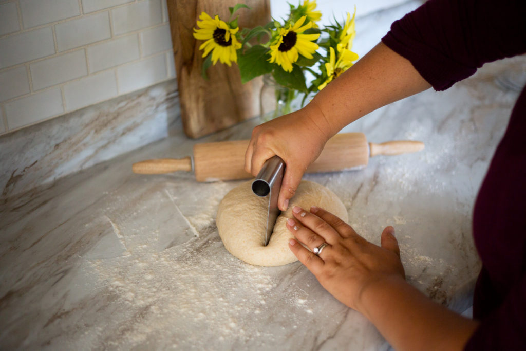 hands cutting dough with dough scraper 