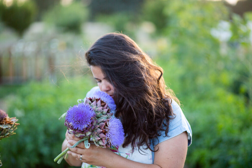 woman smelling artichoke flowers