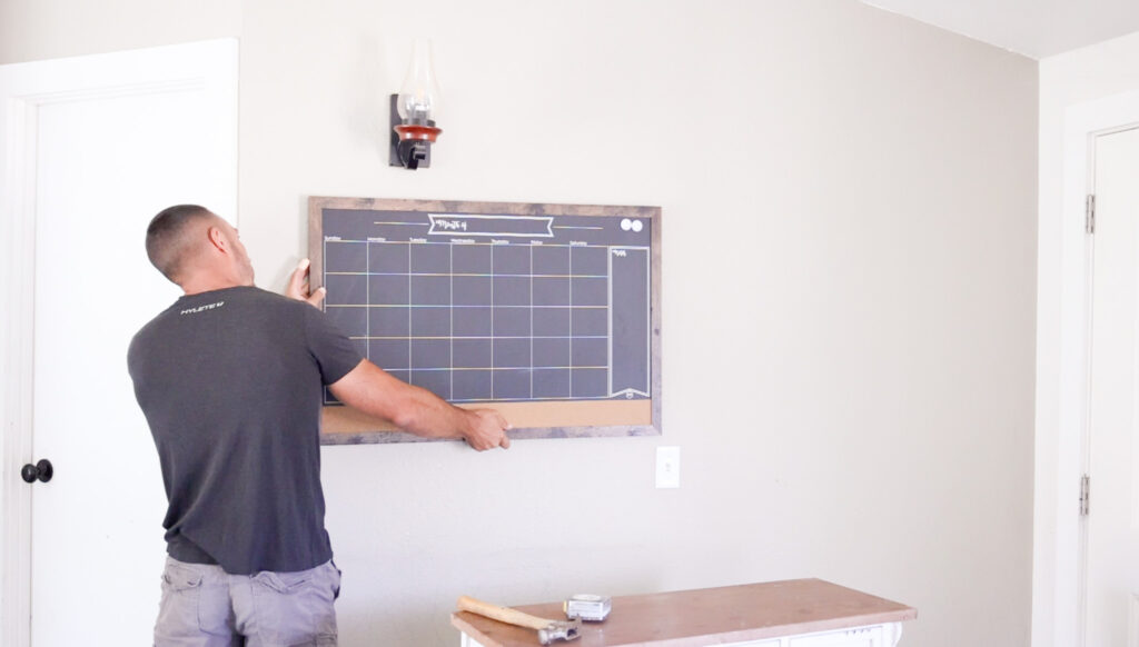 man hanging chalkboard calendar